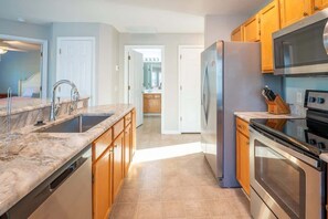 A modern kitchen with a marble countertop, stainless steel appliances, and wooden cabinets.