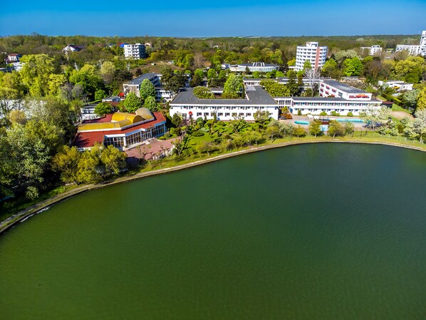 A lakeside hotel with a swimming pool, surrounded by greenery and a few buildings. - Complex Tismana All Inclusive (Jupiter)
