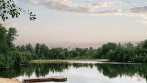 A tranquil lakeside scene with a wooden dock extending into the water, surrounded by dense greenery and a clear sky. - Ski-In/Ski-Out Mont-Blanc Condo w/ Pool & Lake Access (Mont-Blanc)