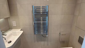 Un baño con un lavabo blanco, un toallero de cromo y un inodoro blanco.