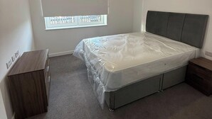 Un dormitorio con una cama individual, una ventana con persianas, una mesita de noche y un armario.