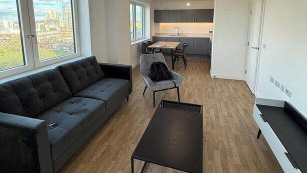 Una sala de estar moderna con un sofá, una mesita de centro y vistas de la ciudad a través de amplios ventanales.