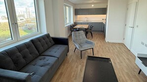 Una sala moderna con un sofá, una mesa de centro y un comedor con una mesa y sillas.