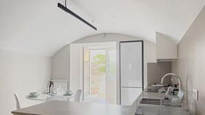 Una cocina moderna con una isla central, horno empotrado y comedor con mesa y sillas.