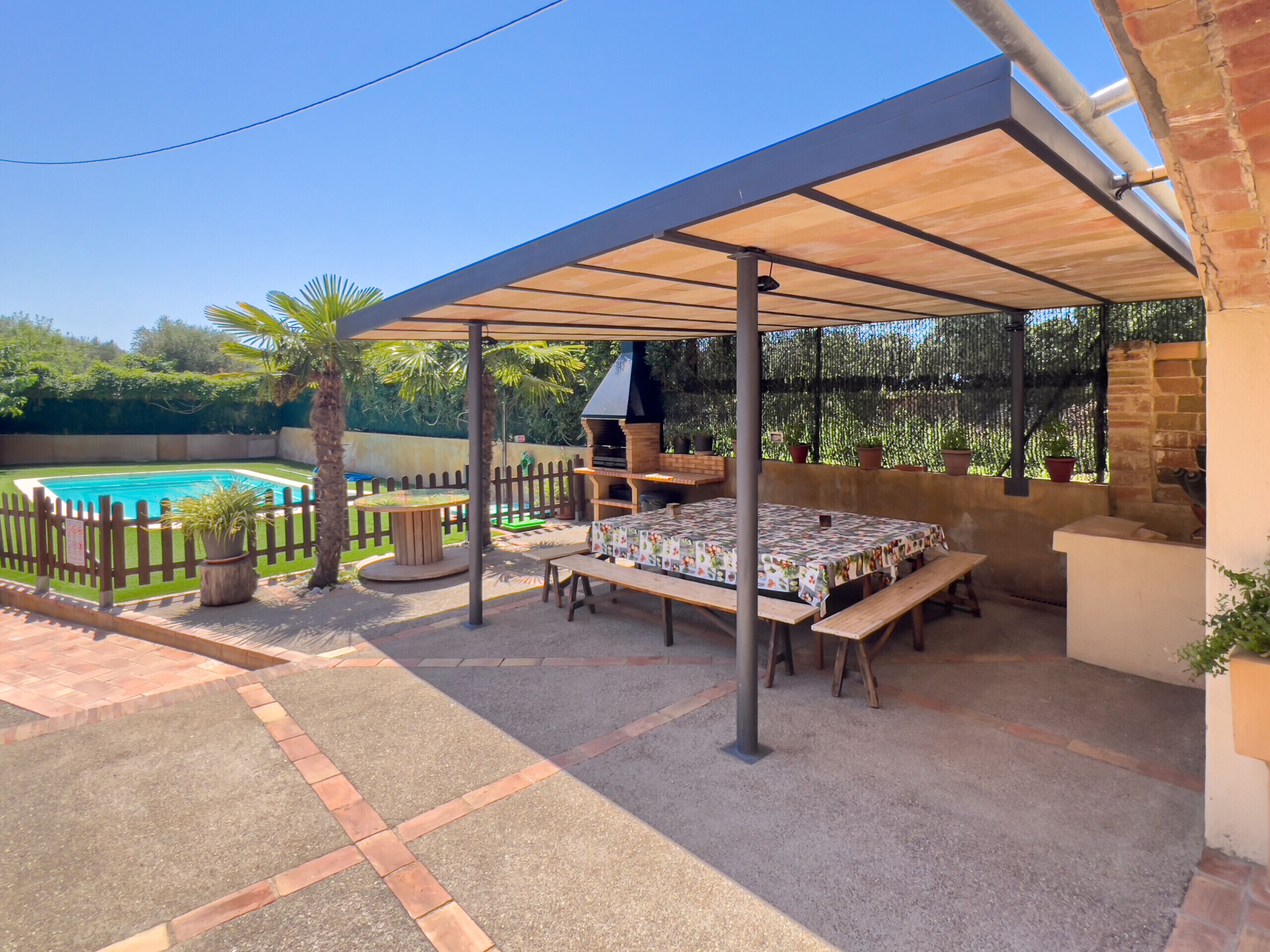 A covered patio area with a pool, outdoor seating, and a barbecue grill.