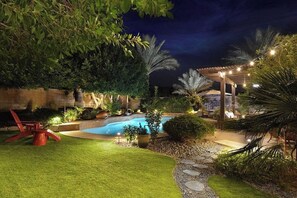 A nighttime outdoor area with a swimming pool, a covered seating area, and a stone pathway. - Private Saltwater Pool & Hot Tub Oasis w/ WiFi (La Quinta)