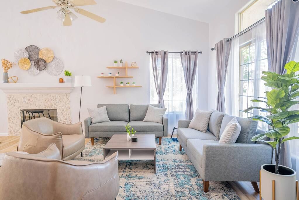 A living room with a fireplace, sofas, a coffee table, and a ceiling fan.