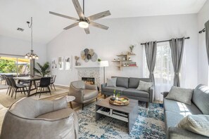 A modern living room with a fireplace, a dining area, and a ceiling fan. - Private Saltwater Pool & Hot Tub Oasis w/ WiFi (La Quinta)