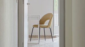 Un pasillo con una silla y una puerta que da a un balcón.