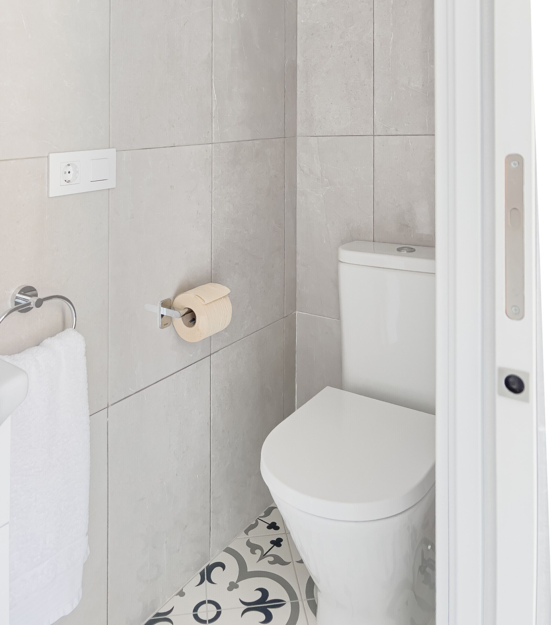 A bathroom with a toilet, a towel rack, and a toilet paper holder on the wall.