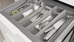 Un cajón con varios compartimentos que contiene diferentes utensilios de cocina.