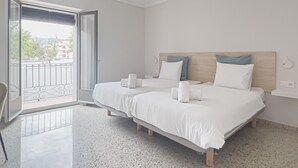 Habitación de hotel con dos camas, un balcón y un ventilador de techo.