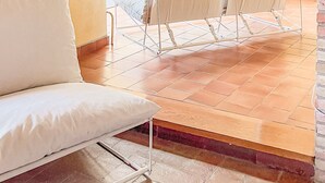 Un rincón exterior acogedor con un sofá blanco y una mesa bajo un arco de ladrillo.