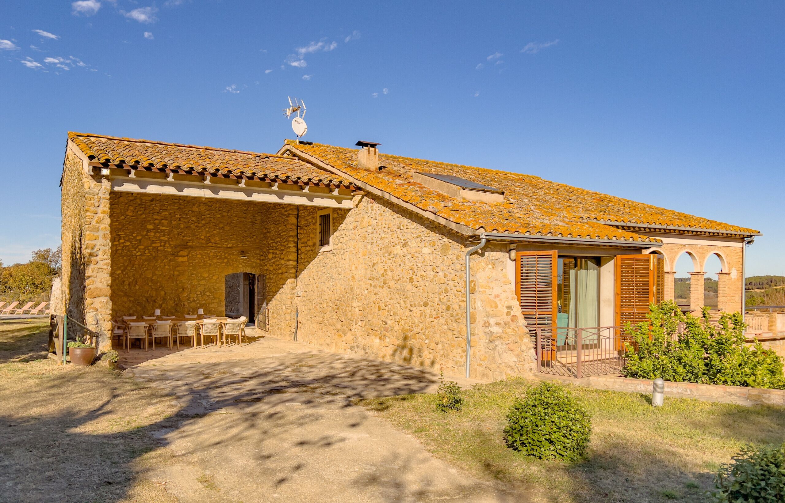 A stone building with a tiled roof, outdoor seating area, and a small garden.