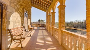 Un espacio al aire libre techado con paredes de piedra, bancos de madera y vistas al paisaje.