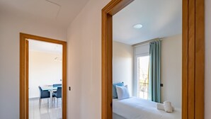 A hotel room with a bed, a window with curtains, a desk with a chair, and a view of the outdoors.