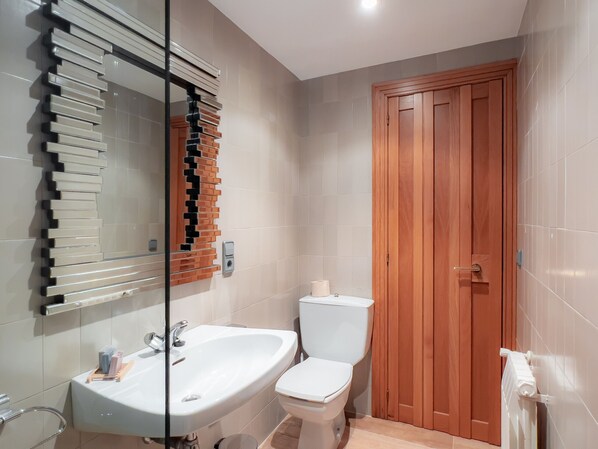 A bathroom with a white sink, a toilet, and a wooden door.