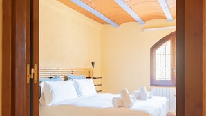 Un dormitorio con estructura de cama de madera, ropa de cama blanca y una ventana con vistas al exterior.