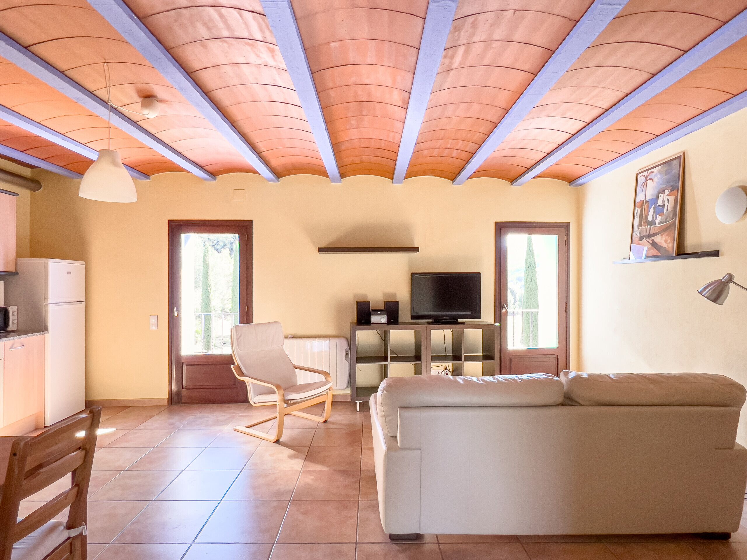 Una sala de estar con un sofá, un televisor y un comedor con una mesa y sillas.