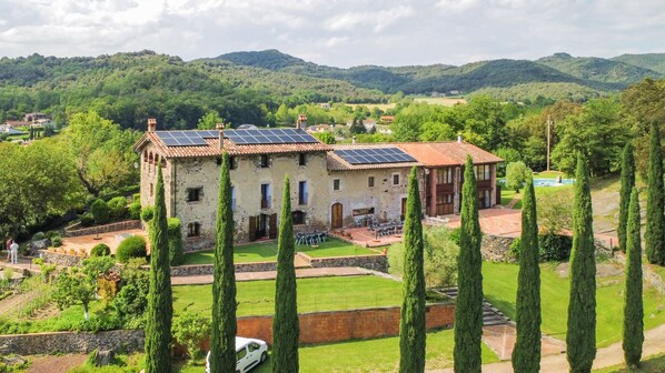 Surrounded by lush greenery and cypress trees, this property offers a serene and picturesque setting with a well-maintained garden and patio area.