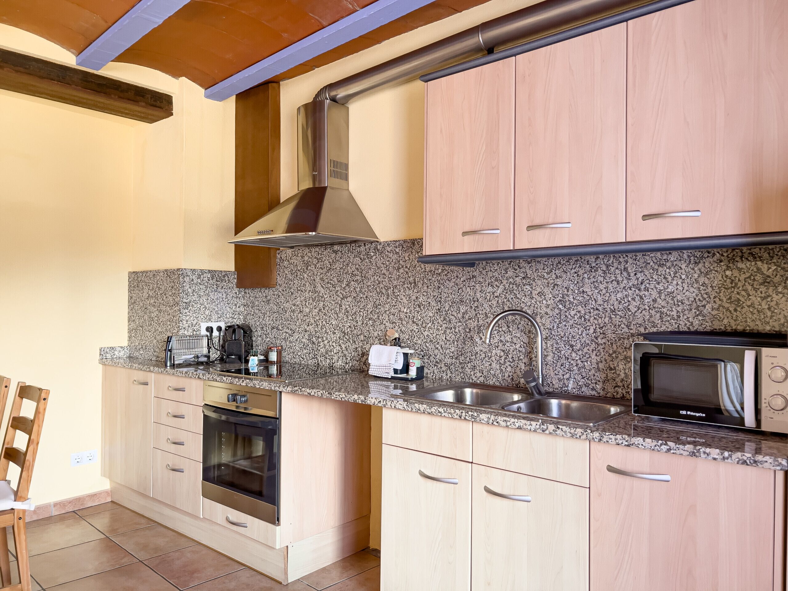 Una cocina moderna con encimeras de granito, electrodomésticos de acero inoxidable y armarios de madera.