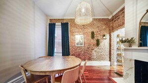 Comedor con una mesa redonda de madera y sillas, pared de ladrillo y chimenea.
