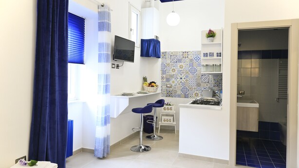 Une cuisine compacte avec un mur recouvert de carreaux, un petit coin bar avec des tabourets et un évier.