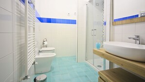 Une salle de bain moderne équipée de toilettes, d’un bidet et d’un grand lavabo installé sur un plan de travail en bois.