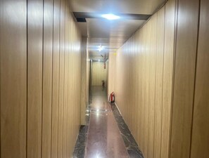 Stylish hallway with wooden paneling and polished floors leads to a door.