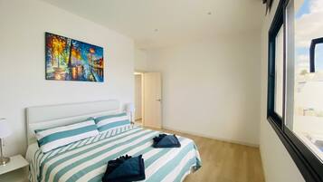 Habitación de hotel con cama, un cuadro en la pared y ventana con vistas a edificios.