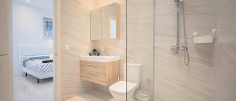 Une salle de bain moderne avec une douche à parois de verre, des toilettes blanches et un meuble-lavabo en bois.