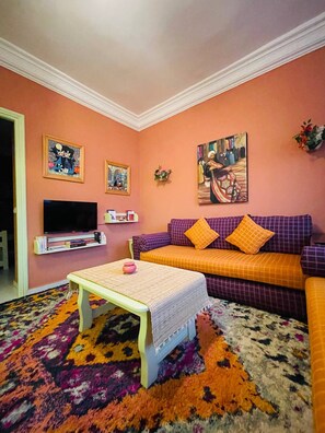 A living room with a sofa, television, and artwork on the walls.