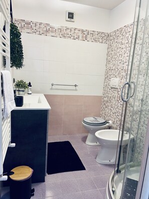 Une salle de bain comprenant des toilettes, un bidet et un espace douche.