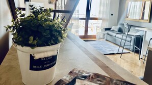 A living room with a potted plant, a sofa, a table, and a chair.