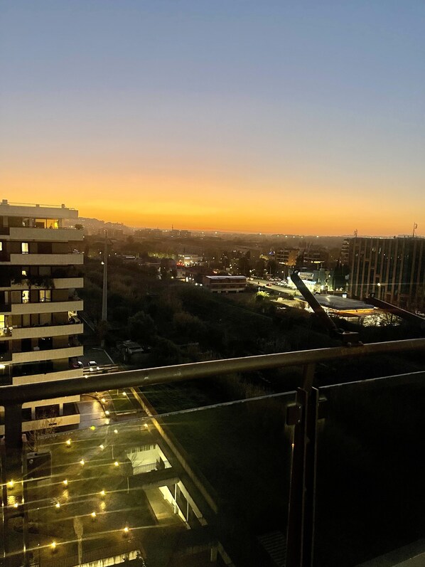 Un immeuble de grande hauteur doté de nombreux balcons et offrant une vue sur un coucher de soleil au-dessus d’une ville.