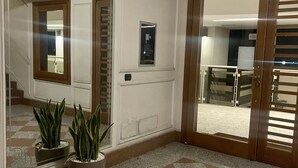 A lobby with a checkered floor, a large mirror, and a potted plant.