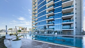 Un edificio moderno con piscina, zona de estar al aire libre y cielo despejado.