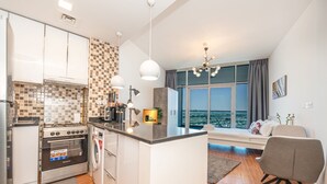 Una cocina moderna con horno integrado, lavadora y cafetera. Hay un comedor con vistas a la ciudad.