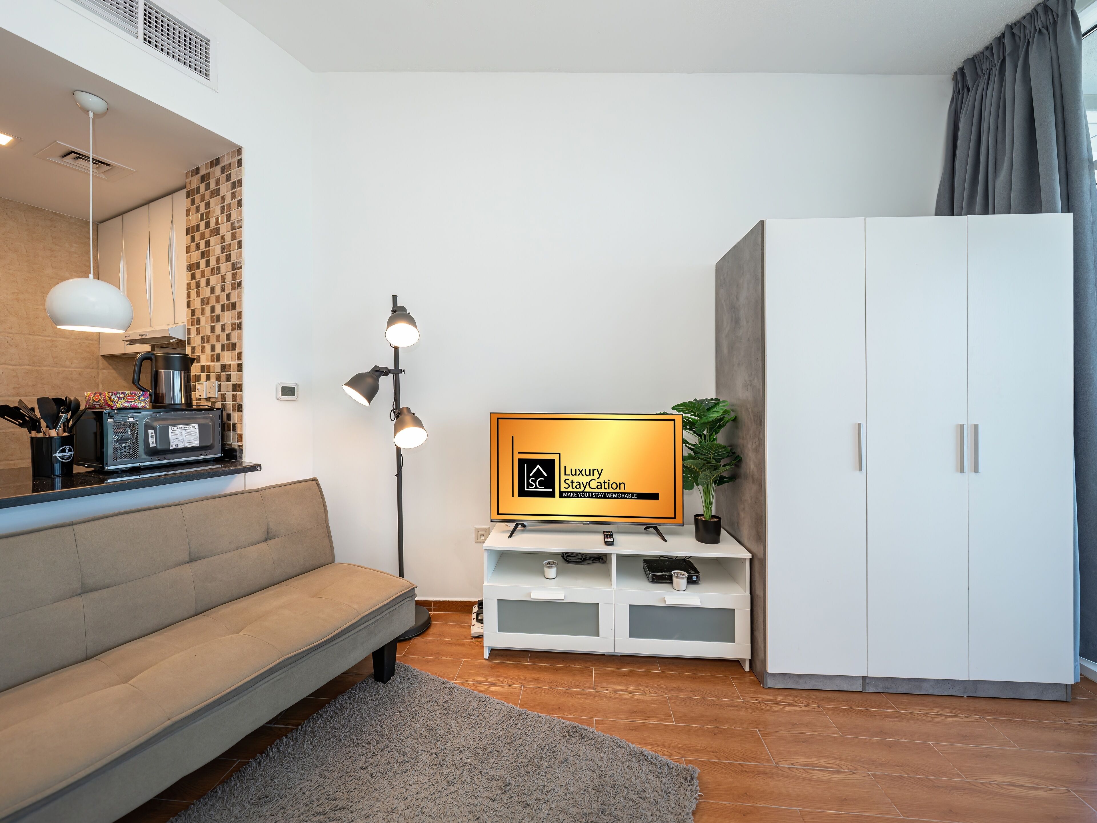 A modern living room with a sofa, a TV, a coffee machine, and a cabinet.