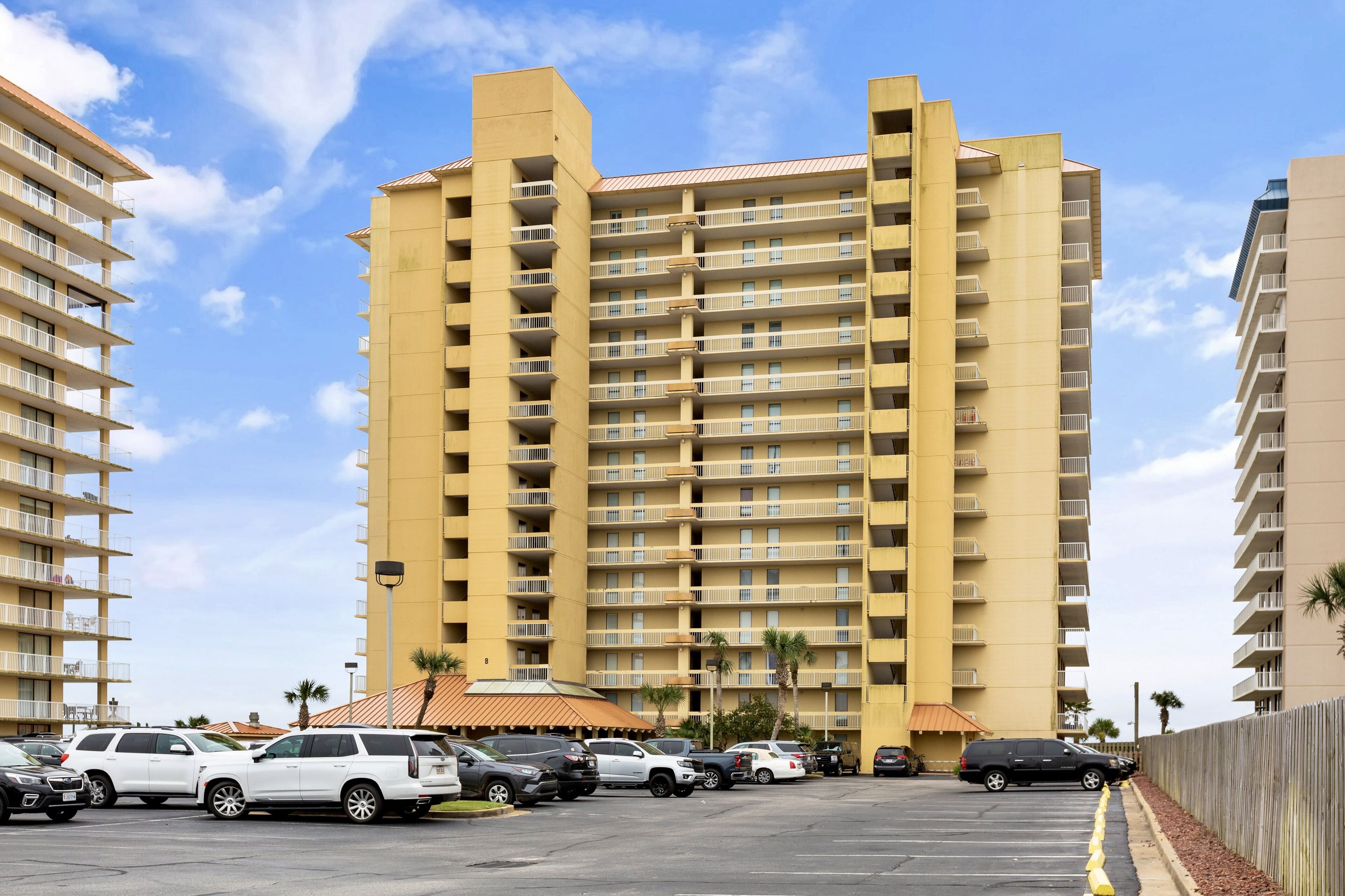 A multi-story hotel with a parking lot in front.