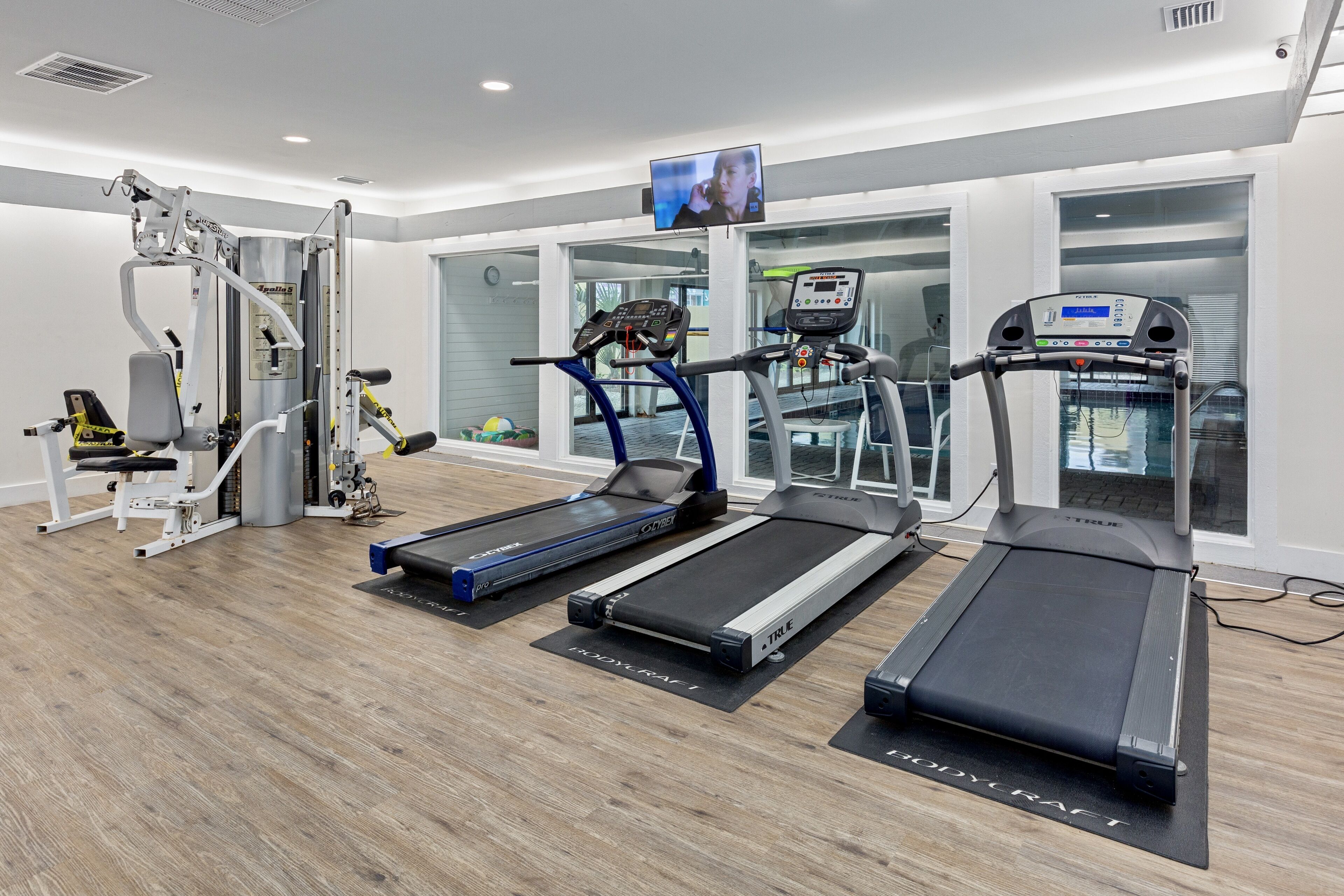 A modern gym with treadmills, a weight machine, and a TV screen.