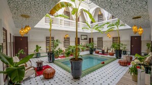 Un patio interior espacioso con piscina, plantas en macetas y zonas de estar.