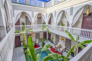 Un patio de varios niveles con arcos blancos, plantas en macetas y suelo de baldosas.