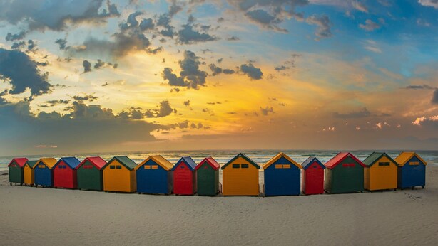 Una hilera de cabañas de playa coloridas a lo largo de la costa.