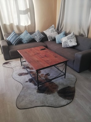 A living room with a sofa, a wooden coffee table, and a shaggy rug. - Dawson's Creek Muizenberg (Cape Town)