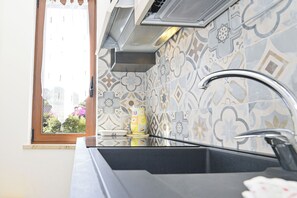 A kitchen with a window, patterned tiles, a sink, and a faucet.