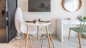 A modern kitchen with a dining area, a flat-screen TV, and a round mirror. - Charming Studio Escape With City View (Dubai)