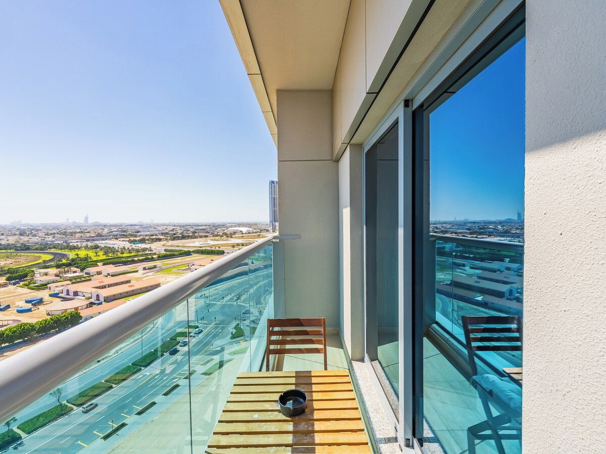 A balcony with a view of a cityscape, a wooden table, and a chair.