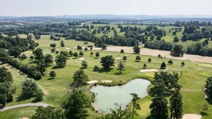 An aerial view of a golf course with multiple bunkers, a pond, and surrounding greenery. - The Boathouse, Orchardleigh Estate
 (Frome)