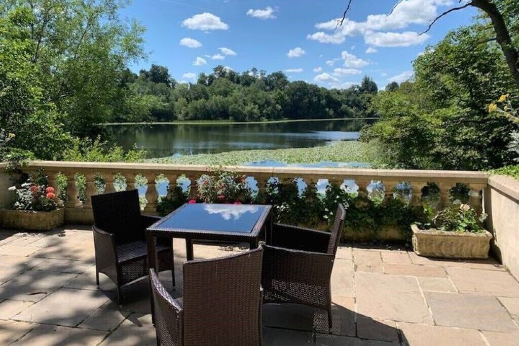 An outdoor patio with wicker furniture and a view of a lake.
